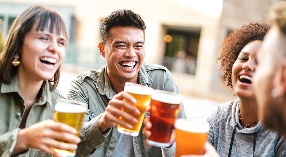 Four friends smile while drinking beer 